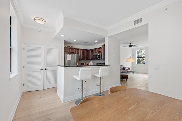 kitchen with light hardwood / wood-style floors, ceiling fan, stainless steel appliances, crown molding, and kitchen peninsula