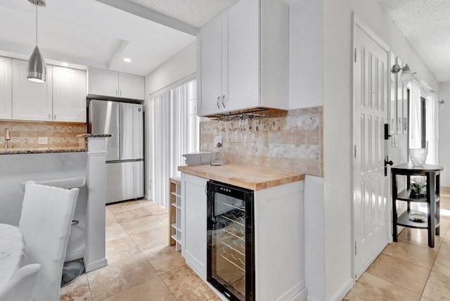 kitchen with wine cooler, white cabinets, stainless steel refrigerator, butcher block counters, and pendant lighting