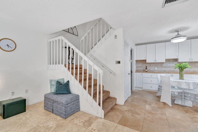 interior space with white cabinets, light tile patterned floors, and tasteful backsplash