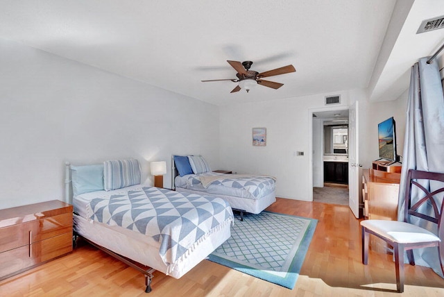 bedroom with light hardwood / wood-style floors, connected bathroom, and ceiling fan