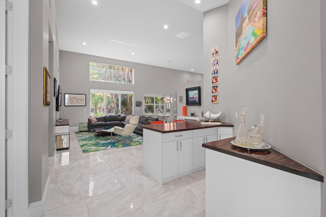 kitchen with white cabinetry, a towering ceiling, and kitchen peninsula