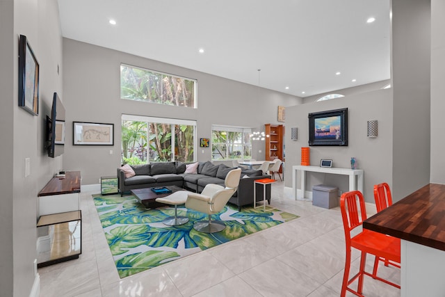 tiled living room featuring a high ceiling and a chandelier