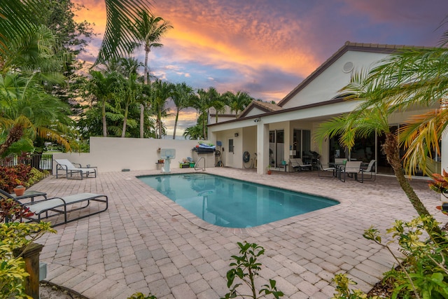 pool at dusk featuring a patio area