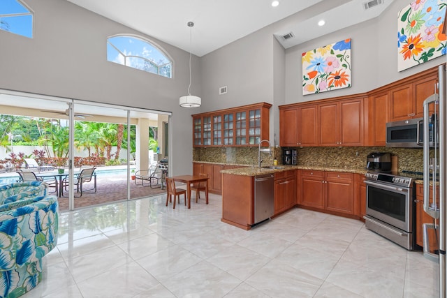 kitchen with high vaulted ceiling, stainless steel appliances, sink, and kitchen peninsula