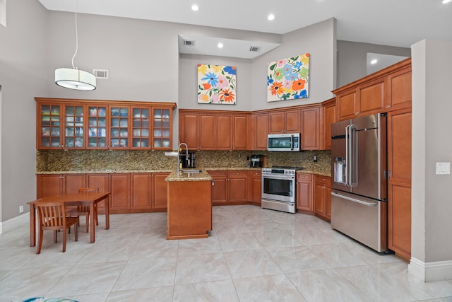 kitchen with tasteful backsplash, light stone countertops, a kitchen island, stainless steel appliances, and a high ceiling