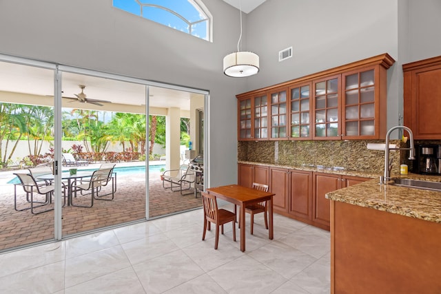 tiled dining room with sink, a high ceiling, and ceiling fan