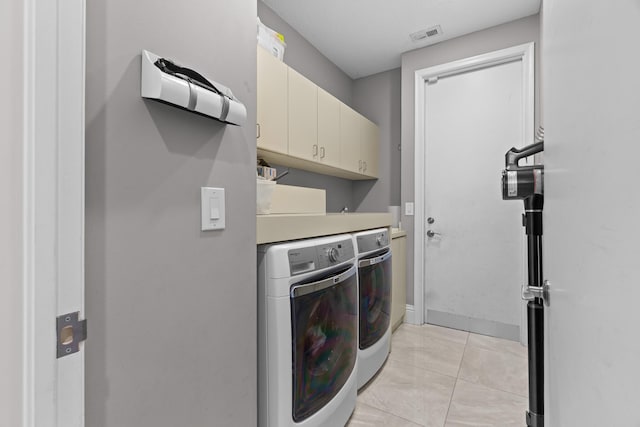 laundry room with light tile patterned flooring, washer and dryer, and cabinets