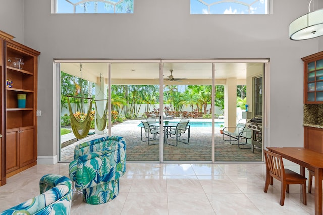 dining space featuring ceiling fan, a healthy amount of sunlight, and a high ceiling