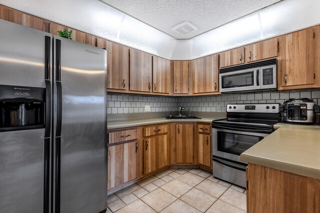 kitchen featuring stainless steel appliances, decorative backsplash, sink, and light tile patterned floors