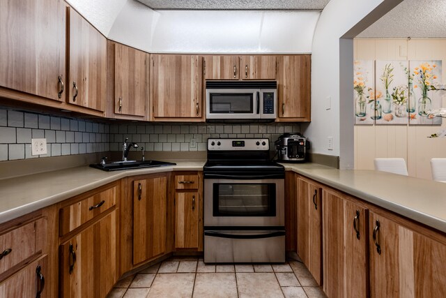 kitchen with tasteful backsplash, appliances with stainless steel finishes, sink, and a textured ceiling