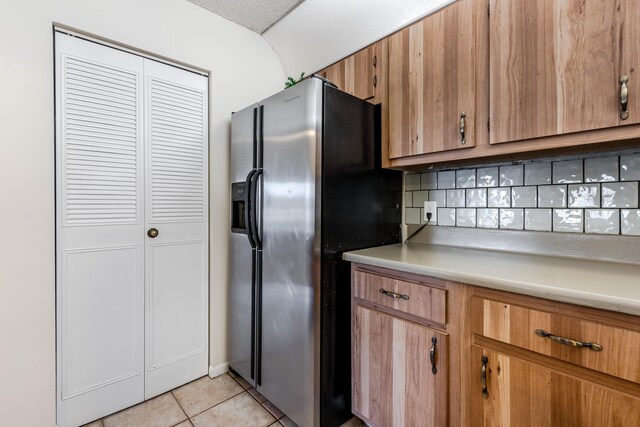 kitchen featuring light tile patterned flooring, stainless steel fridge with ice dispenser, and decorative backsplash