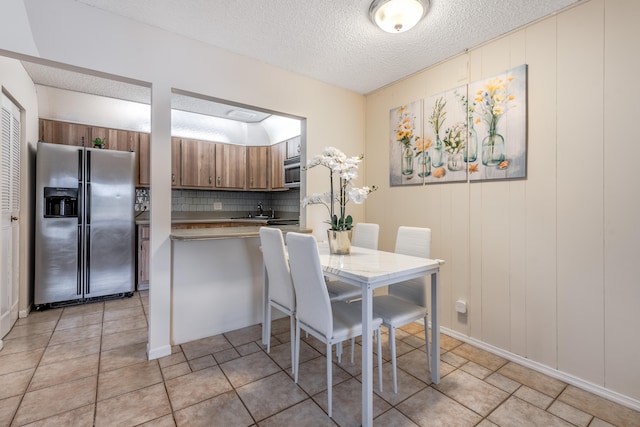 dining room featuring light tile patterned flooring, sink, and a textured ceiling