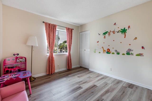 game room with light hardwood / wood-style flooring and a textured ceiling