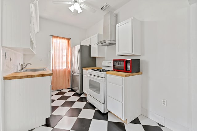 kitchen with sink, white cabinets, white gas range, wall chimney exhaust hood, and ceiling fan