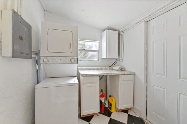 washroom featuring stacked washer and clothes dryer, electric panel, and cabinets