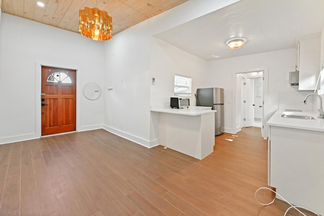 foyer entrance with sink, light wood-type flooring, wooden ceiling, and a notable chandelier