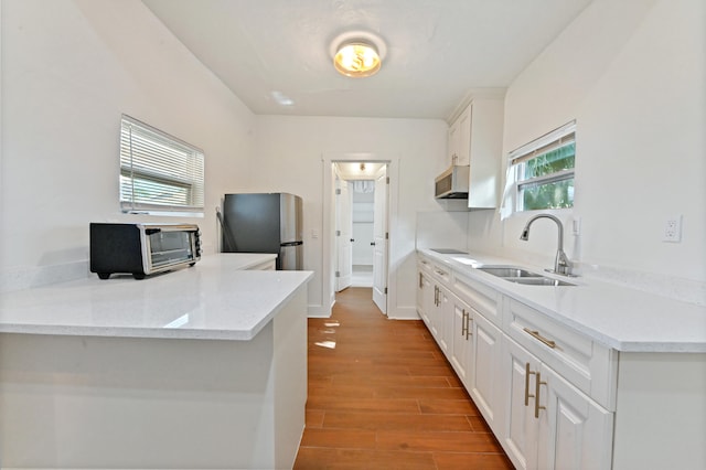 kitchen featuring sink, white cabinetry, light stone countertops, ventilation hood, and stainless steel fridge