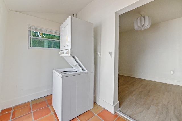 clothes washing area with stacked washer and clothes dryer and light tile patterned floors