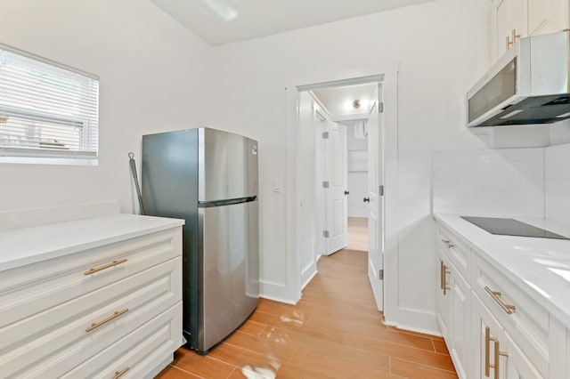 kitchen featuring stainless steel fridge, white cabinetry, and black electric cooktop