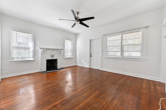 unfurnished living room with a tile fireplace, ceiling fan, and dark hardwood / wood-style flooring