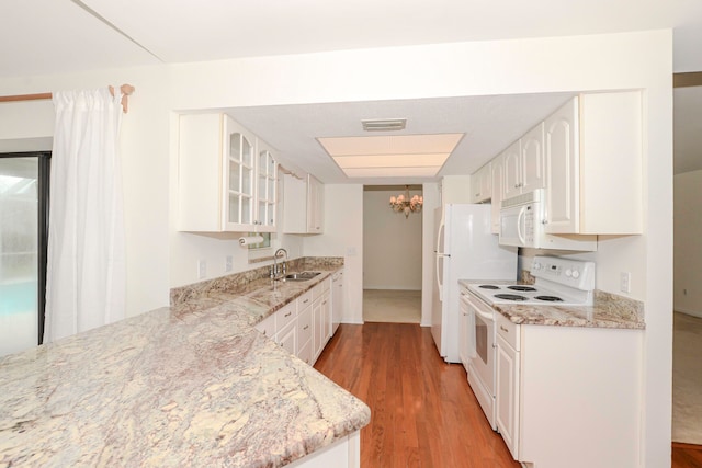 kitchen with white cabinets, white appliances, light stone countertops, and light hardwood / wood-style flooring