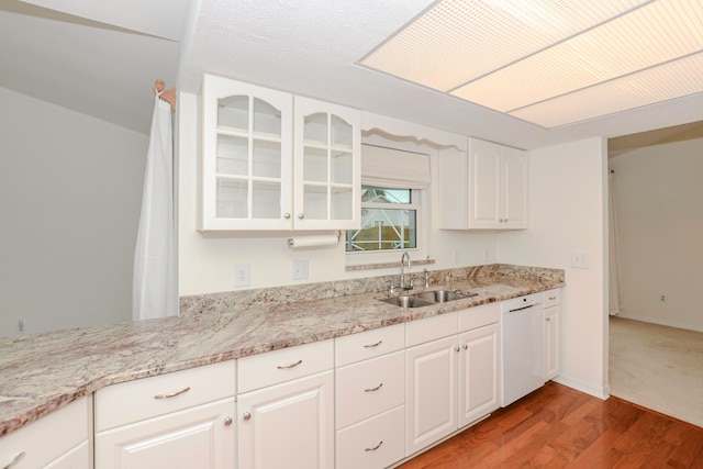 kitchen with light stone counters, white dishwasher, sink, white cabinetry, and light hardwood / wood-style flooring