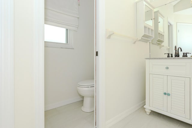 bathroom with toilet, vanity, and tile patterned flooring