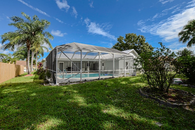 rear view of property featuring a yard and glass enclosure