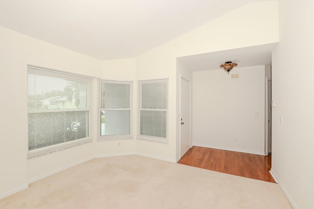 carpeted empty room featuring vaulted ceiling