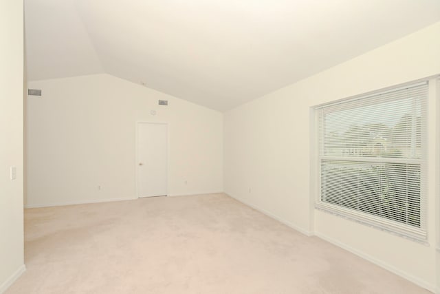 empty room with light colored carpet and lofted ceiling