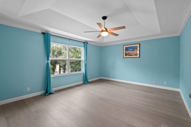 empty room with a tray ceiling, crown molding, hardwood / wood-style flooring, and ceiling fan