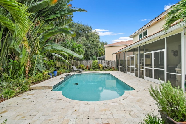 view of swimming pool with a sunroom and a patio area