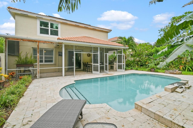 back of house featuring a patio area, a sunroom, an outdoor pool, and stucco siding