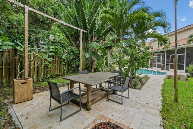 view of patio / terrace featuring an outdoor pool, a fenced backyard, outdoor dining space, an outdoor fire pit, and a sunroom