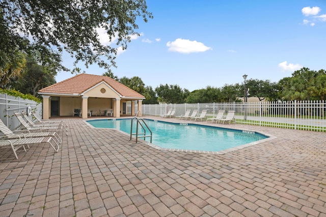 community pool with fence and a patio area
