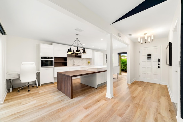 kitchen featuring a kitchen island, oven, white cabinetry, an inviting chandelier, and decorative light fixtures