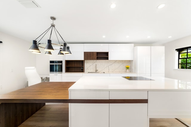 kitchen with stainless steel oven, black electric cooktop, dark hardwood / wood-style floors, hanging light fixtures, and white cabinets