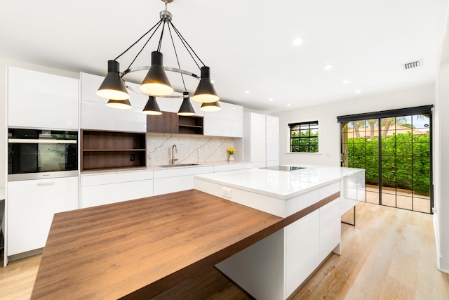 kitchen featuring pendant lighting, oven, white cabinetry, and a kitchen island