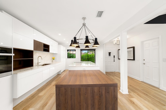 unfurnished living room featuring light hardwood / wood-style floors, a chandelier, and sink