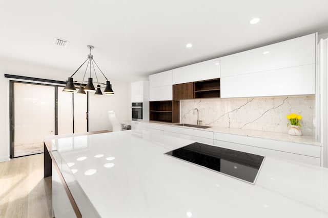 kitchen with sink, decorative light fixtures, oven, white cabinetry, and black electric cooktop