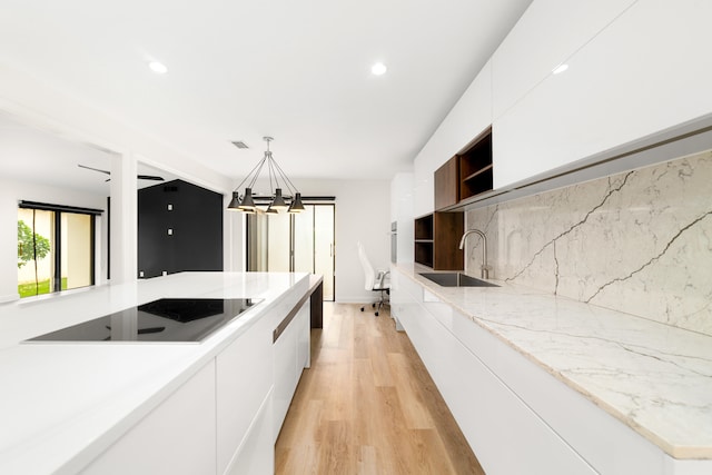 kitchen with white cabinets, hanging light fixtures, sink, light hardwood / wood-style flooring, and a chandelier