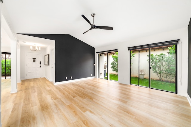 unfurnished living room with ceiling fan with notable chandelier, lofted ceiling, and light hardwood / wood-style flooring