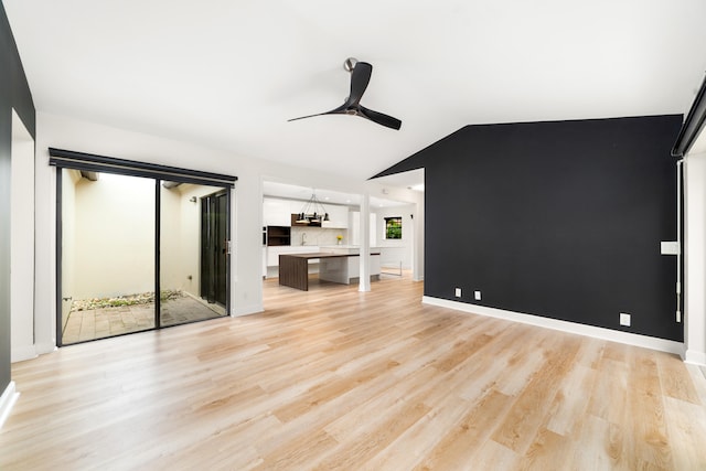 unfurnished living room with lofted ceiling, ceiling fan with notable chandelier, and light wood-type flooring