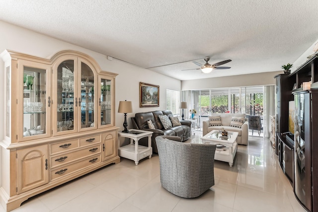 living room with ceiling fan, a textured ceiling, and light tile patterned floors