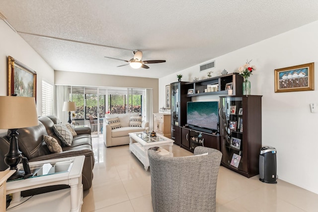 living room featuring ceiling fan, light tile patterned floors, and a textured ceiling