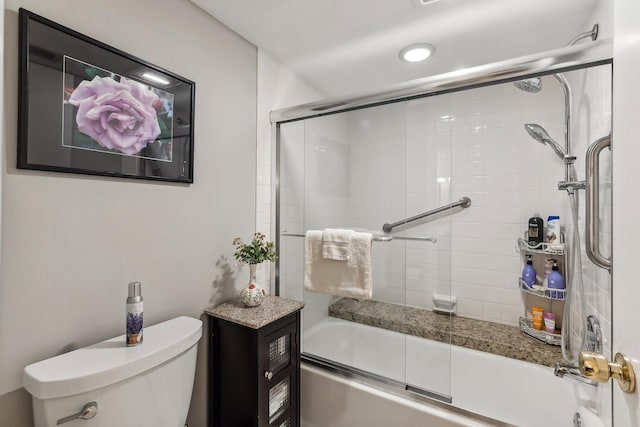 bathroom with bath / shower combo with glass door and toilet