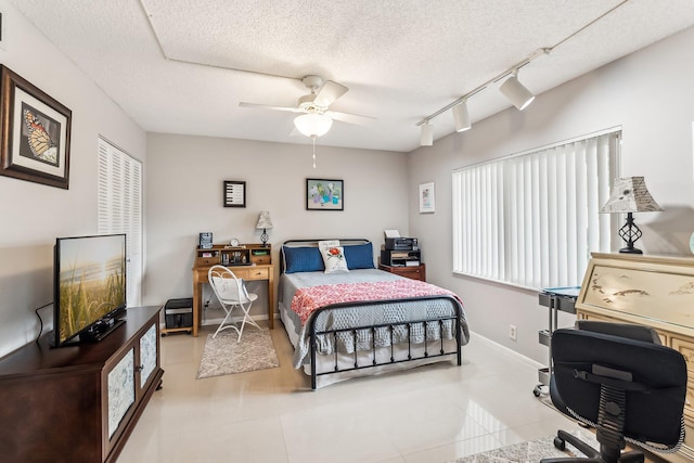 bedroom with ceiling fan, a textured ceiling, light tile patterned flooring, and rail lighting