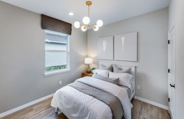 bedroom with a notable chandelier, wood finished floors, and baseboards