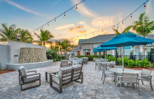 patio terrace at dusk featuring fence, an outdoor hangout area, and outdoor dining space