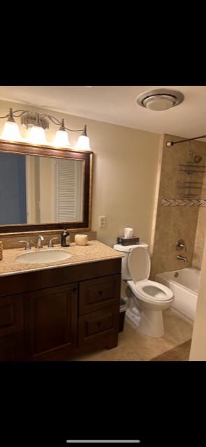 full bathroom featuring vanity, tiled shower / bath combo, toilet, and tile patterned flooring